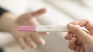 Closeup of a woman's hand holding up a pregnancy test kit with a negative